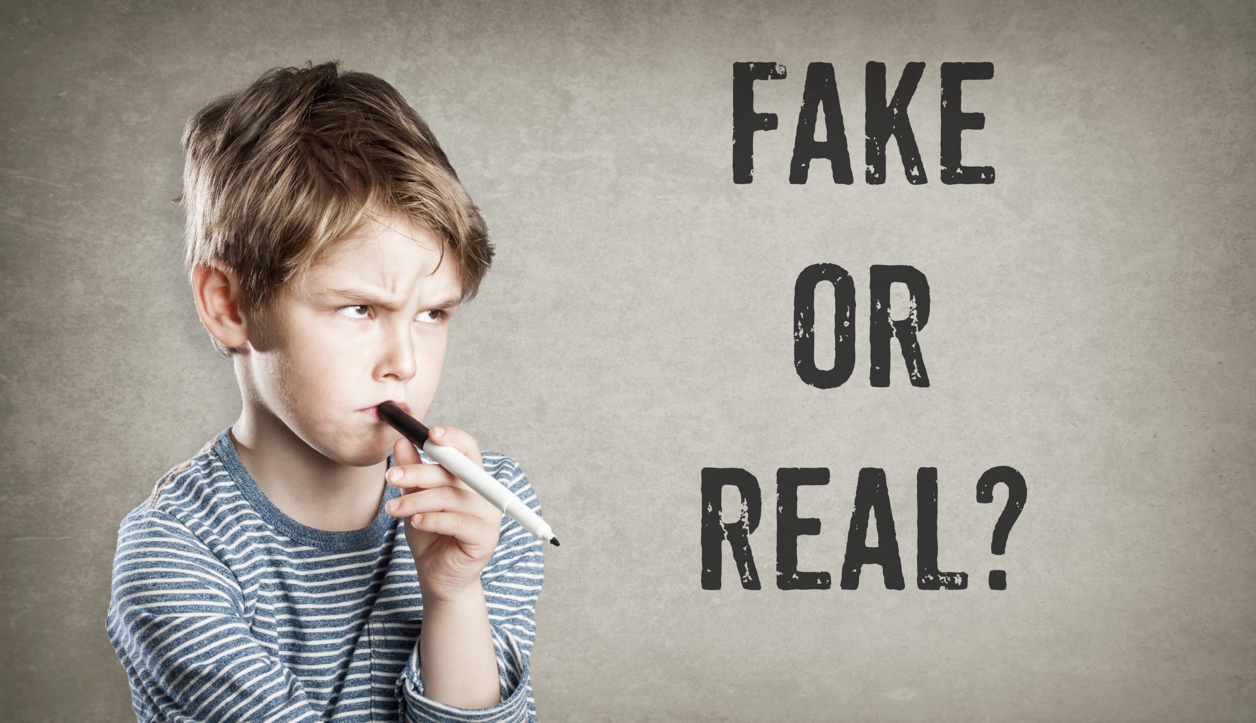 A boy with a pen in his mouth thinking with the words, "Fake or Real" on the left"